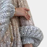 Silver sequin bridal shawl draped elegantly over a woman's shoulders, showcasing intricate embellishments and sparkling design. The shawl complements an evening or bridal outfit, adding a touch of glamour and sophistication.