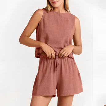 Woman wearing a sleeveless black romper with a drawstring waist, standing against a plain background.