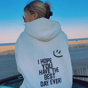White smiley face hoodie featuring an inspirational quote, displayed in a leisure setting, with a focus on the comfort and casual style of the sweatshirt.