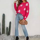 A blue and white crewneck sweater featuring a star pattern, worn by a person styled casually with jeans and sunglasses, showcasing a relaxed outfit.