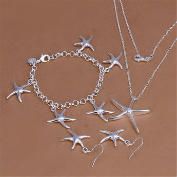 Sterling silver starfish jewelry set including a necklace, bracelet, and earrings displayed on a rustic wooden background.