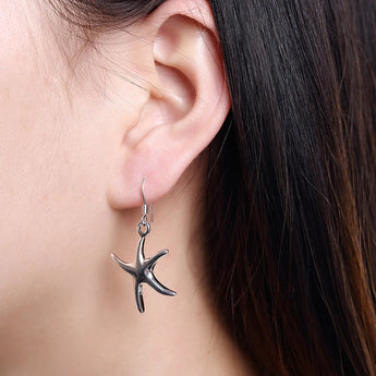 Sterling silver starfish jewelry set including necklace, bracelet, and earrings displayed on a model.