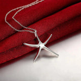 Sterling silver starfish jewelry set including a necklace, bracelet, and earrings against a red background.