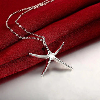 Sterling silver starfish jewelry set including a necklace, bracelet, and earrings against a red background.