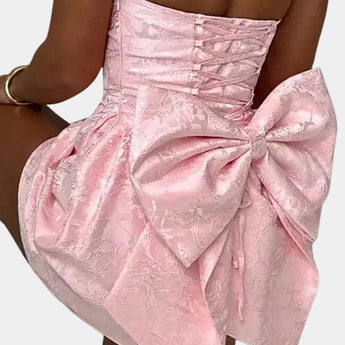 Strapless white satin cocktail dress with lace overlay, featuring a large bow at the waist, designed as a one-piece garment.