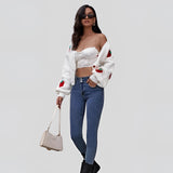 Women's trendy V-neck strawberry knit cardigan worn with denim jeans, highlighting the garment's waist and sleeve details.