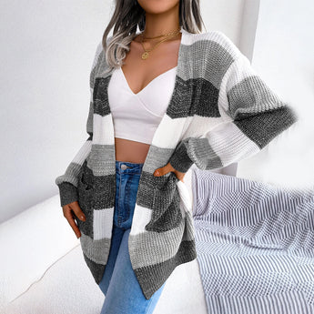 Striped black and white long sleeve women's cardigan worn by a model. The cardigan features a stylish design with bold stripes, extending to the waist and thighs, perfect for fall fashion.