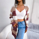 Striped black and white long sleeve women's cardigan displayed on a model. The knitwear features a classic pattern and is styled for fall fashion, highlighting the sleeves and neckline.