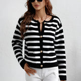 A person wearing a striped blue and white knit cardigan sweater with a button-up design, featuring a collar and sleeves.