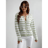 A smiling woman wearing sunglasses and a striped blue and white knit cardigan with button-up details, featuring long sleeves and a casual chic style.