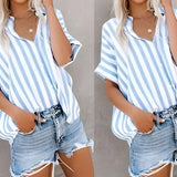 A woman wearing a striped blue and white V-neck summer blouse paired with distressed denim shorts.