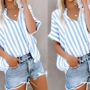 A woman wearing a striped blue and white V-neck summer blouse paired with distressed denim shorts.