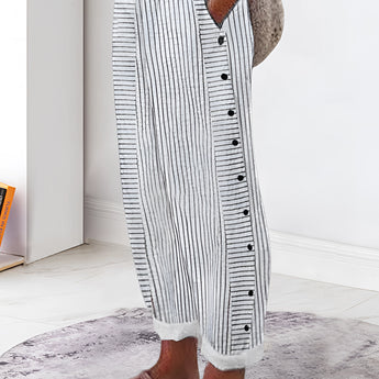 Striped button-up lounge pants in grey, styled for summer with lightweight fabric; shown on a model standing indoors on a wooden floor.