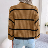 Tan and black striped chunky turtleneck sweater displayed on a wooden surface, showcasing its long sleeves and cozy collar, ideal for casual winter wear.
