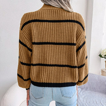 Tan and black striped chunky turtleneck sweater displayed on a wooden surface, showcasing its long sleeves and cozy collar, ideal for casual winter wear.