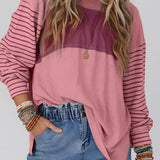 
A woman wearing a striped color block long sleeve casual pullover sweater, featuring a mix of colors and a relaxed fit. She is smiling and posing, showcasing the sweater's fashionable design and comfortable fabric.