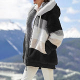 Striped fleece women's hooded Sherpa jacket in a warm colorblock design, worn by a person outdoors in a snowy environment. The jacket features a plush texture and includes sleeves and a hood, providing warmth and comfort.
