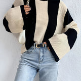 A women's chunky knit sweater with a striped pattern, featuring bell sleeves. The sweater is styled with a loose fit around the shoulders and neck, and the material appears soft and cozy. The model is wearing the sweater in a size large, showcasing its casual and stylish appearance. The sweater is paired with a simple hairstyle and does not include any visible accessories.
