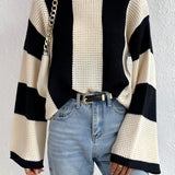 Striped knit sweater featuring chunky knit texture and bell sleeves, styled with jeans and highlighting a fashionable look.