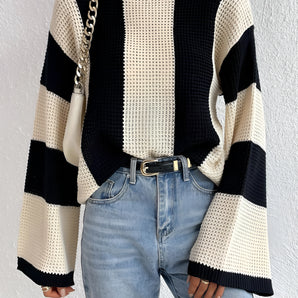 Striped knit sweater featuring chunky knit texture and bell sleeves, styled with jeans and highlighting a fashionable look.
