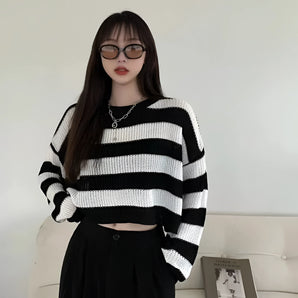 
A stylish oversized knit sweater with black and white stripes, modeled by a person wearing sunglasses. The focus is on the sweater's loose fit and trendy design, perfect for autumn fashion. The sweater features long sleeves and a comfortable neckline.