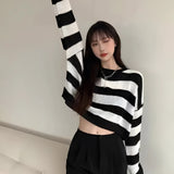 Striped oversized black and white knit sweater worn by a person, highlighting the trendy autumn fashion design with long sleeves and relaxed fit.