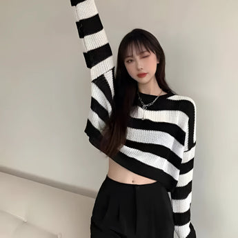 Striped oversized black and white knit sweater worn by a person, highlighting the trendy autumn fashion design with long sleeves and relaxed fit.