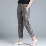A woman wearing gray striped slim fit ankle-length trousers in size XXL paired with a blazer, showcasing a stylish and monochrome fashion look.