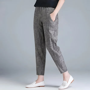 A woman wearing gray striped slim fit ankle-length trousers in size XXL paired with a blazer, showcasing a stylish and monochrome fashion look.