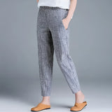 A woman wearing blue striped slim fit ankle-length trousers in a stylish monochrome fashion, showcasing the XXL size.