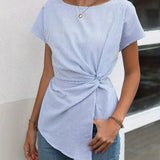 Woman wearing blue and white striped twist-front blouse with long sleeves and a collar, showcasing a casual chic style.