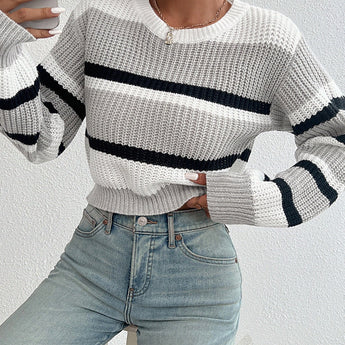 Striped women's black and white crew neck sweater worn by a person, paired with jeans, showcasing a chic winter knitwear style with a focus on the shoulder and neck area.