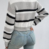 Striped women's black and white crew neck sweater worn by a model. The sweater features a chic winter knitwear design, paired with jeans. The model's shoulder and arm are visible, showcasing the sweater's fit and style.