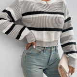 Striped black and white crew neck sweater worn by a woman, showcasing chic winter knitwear style, complemented with jeans.