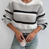 Striped women's black and white crew neck sweater displayed on a mannequin, showcasing its chic winter knitwear design with emphasis on the neckline and shoulder area.