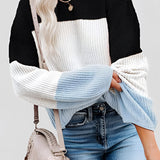 Striped women's color block sweater in black, showcasing a cozy fall fashion knitwear top, worn by a model. The sweater is styled with jeans, highlighting a relaxed yet fashionable look suitable for cooler weather. The model's pose emphasizes the sweater's fit, particularly around the shoulders and arms.