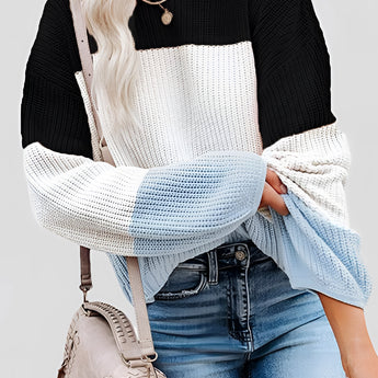 Striped women's color block sweater in black, showcasing a cozy fall fashion knitwear top, worn by a model. The sweater is styled with jeans, highlighting a relaxed yet fashionable look suitable for cooler weather. The model's pose emphasizes the sweater's fit, particularly around the shoulders and arms.
