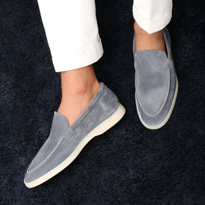 Stylish grey suede men's slip-on loafers on a person's feet, showcasing lightweight casual shoes.