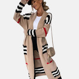 
A woman wearing a stylish oversized knit cardigan in beige and black stripes, featuring long sleeves and an open front design; the cardigan is in a Brown XXL size, showcasing a relaxed fit.