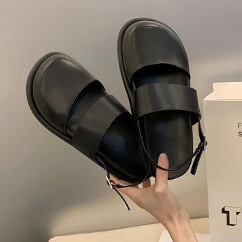 Stylish women's black platform orthopedic sandals with ankle strap, shown worn on a model's feet, highlighting comfort and fashion-forward design.