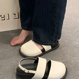 Stylish women's black platform orthopedic sandals featuring an ankle strap, displayed on a model's feet against a grey flooring background.