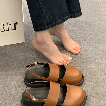 Stylish women's black platform orthopedic sandals with ankle strap shown on a model's foot and lower leg, featuring a sleek design and comfortable fit.