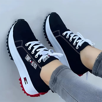 Stylish women's white sneakers with a distinctive red sole, suitable for urban fashion. The image features the Nero variant in size 43, showcasing the shoe's sleek design and trendy appearance, ideal for both casual and outdoor activities.