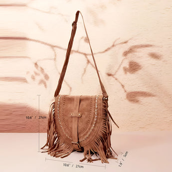 Tan suede fringe boho crossbody bag with tassels, styled in a casual bohemian fashion, against a natural wooden and plant-filled background.