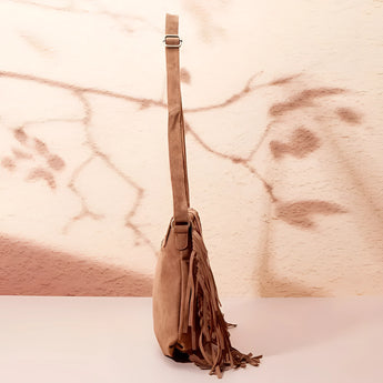 Tan suede fringe boho crossbody bag with tassels, styled with a wood background, showcasing its bohemian design and fashion accessory appeal.