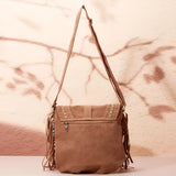 Tan suede crossbody bag with bohemian fringe detailing and tassels, featuring a long strap for shoulder wear.