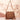 Tan suede fringe crossbody bag with tassel details, styled as a boho shoulder bag.