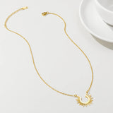 Gold Sunburst Pendant Necklace displayed on a white surface; features a celestial design with intricate detailing, resembling body jewelry and fashion accessory.