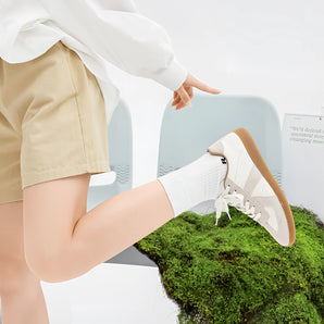 Beige women's sneakers displayed on a person wearing a casual dress, highlighting their eco-friendly and stylish design.
