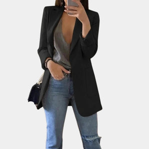 
A woman wearing a tailored black blazer, suitable for office wear, styled with sunglasses. The blazer features long sleeves and a tailored fit, emphasizing the shoulders and waist, paired with jeans. The woman is posing confidently, showcasing the versatile and chic design of the blazer, available in size 3XL.